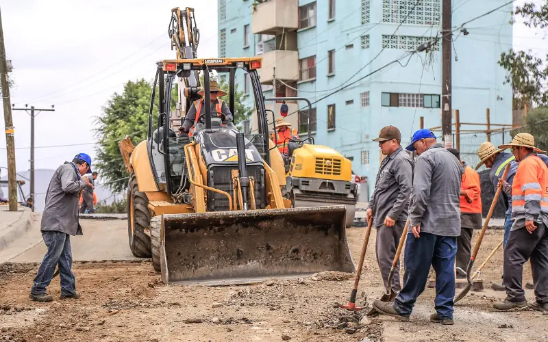 Group of men repairing a street next to a cat bulldozer