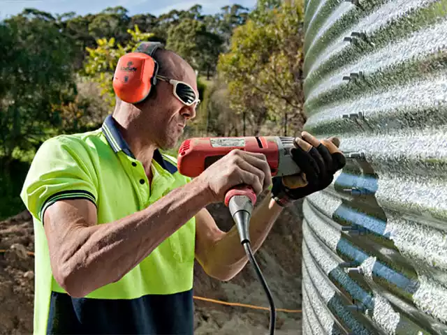 Man installing corrugated tank panel