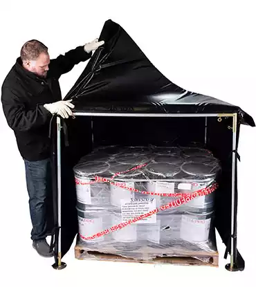Man placing 55 gallon drum in a power blanket hot box